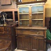 An Edwardian oak two part cabinet bookcase, the moulded top above a pair of glazed panel doors