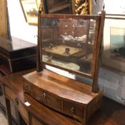 A 19thc mahogany bow front swing mirror raised on square tapered supports with brass urn finials,