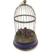 A modern bird automaton with brass wire case, on enamelled circular base, with wind up screw base,