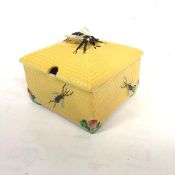 A Crown Devon square shaped honeycomb box with bee mounted finial to top, with yellow ground and