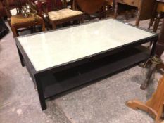 An ebonised two tier rectangular coffee table with inset glass top, on square supports (41cm x 153cm