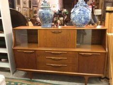 A 1960s/70s teak side cabinet, with fall front cocktail centre flanked by glazed sliding panel