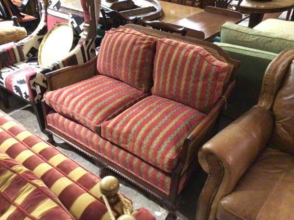 A mahogany framed two seater bergere sofa with double caned panel sides and back, upholstered with