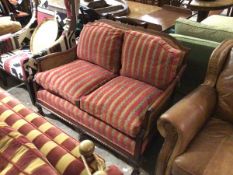 A mahogany framed two seater bergere sofa with double caned panel sides and back, upholstered with