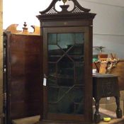 An Edwardian mahogany wall corner cabinet with broken swan neck pediment, with fretwork panels above