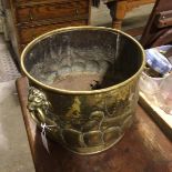 An Edwardian embossed brass circular coal bucket with Viking longboat style chased panel with lion