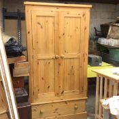 A pine wardrobe, the plain top above a pair of panel doors and single drawer, raised on plinth