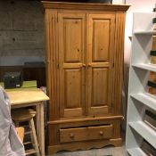 A modern pine wardrobe, the moulded cornice above a pair of inset panel doors, above a single