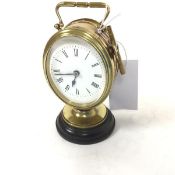 An Edwardian French oval desk alarm clock with handle to top and enamelled dial, with roman