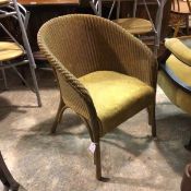 A Lloyd Loom style cane basket chair in gold colour with gold upholstered seat, raised on turned