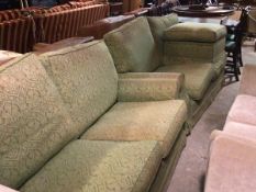 A pair of modern two seater sofas upholstered in cream fabric, with green damask loose covers,