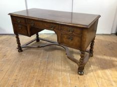 A walnut desk in early 18th century style, the rectangular crossbanded top above an arrangement of