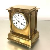 An Edwardian brass mantel clock, the white enamel dial with Roman numerals, signed with retailer's