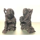 A pair of Chinese carved ebonised or rosewood figures of laughing children, each modelled holding
