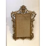 A carved giltwood mirror in the Baroque taste, early 20th century, the rectangular bevelled plate