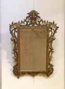 A carved giltwood mirror in the Baroque taste, early 20th century, the rectangular bevelled plate