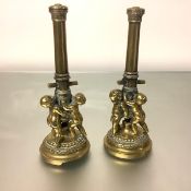 A pair of 19th century bronze table ornaments modelled as putti supporting a cannon barrel, each