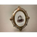 A late 19th century, enamelled, gilt and silvered-brass photograph frame, oval, probably French, the