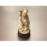 A Japanese carved ivory okimono, late 19th century, depicting a smiling seated Buddhist monk holding