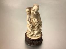 A Japanese carved ivory okimono, late 19th century, depicting a smiling seated Buddhist monk holding