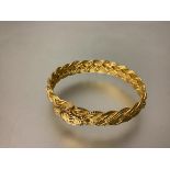 A striking 22ct gold bangle, hinged, of intricate polished and textured woven design, the pin