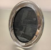 A large George V silver photograph frame, Birmingham 1912, the broad oval frame enclosing a glazed