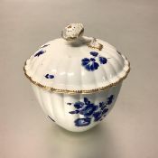 An 18th century porcelain sucrier, the domed fluted cover with floral knop over a fluted body,