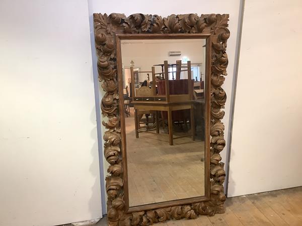 A 19th century carved fruitwood wall mirror, in the Baroque taste, the rectangular plate within a