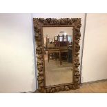 A 19th century carved fruitwood wall mirror, in the Baroque taste, the rectangular plate within a