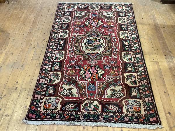 A Bakhtiari hand-knotted wool small carpet, the raspberry-sorbet field with central medallion