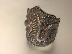 A substantial Chinese silver cuff bangle, chased in high relief with a dragon and flaming pearls,