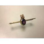 A 9ct gold amethyst bar brooch, c. 1900, the oval-cut stone within a textured ropetwist mount, on