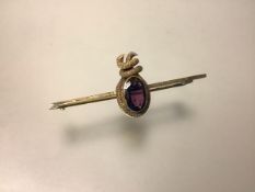 A 9ct gold amethyst bar brooch, c. 1900, the oval-cut stone within a textured ropetwist mount, on
