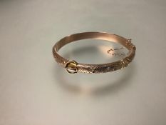 A 9ct gold hinged bangle, early 20th century, of belt and buckle form, foliate engraved, with safety