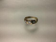 A gentleman's 9ct gold three-stone diamond gypsy-set ring, the round brilliants illusion-set and