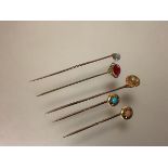 A group of five stick pins, early 20th century, one set with a seed pearl, the pin stamped "10", the