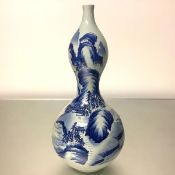 A large Chinese blue and white porcelain vase, of double gourd form, painted with pavilions in a