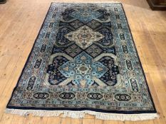 A 20th century carpet of Heriz design, the indigo field with three conjoined medallions in ivory and