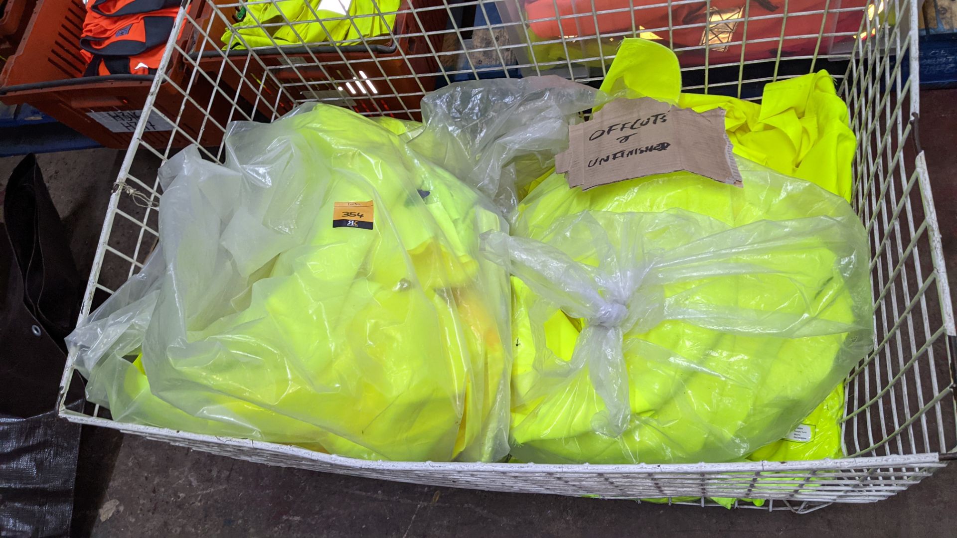 The contents of a cage of off-cuts & unfinished garments, all in yellow hi-vis fabrics. NB cage exc