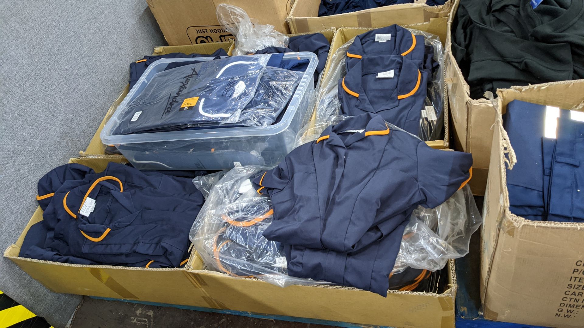 The contents of a pallet of short sleeve zip up navy tops with white or orange collars - this lot co