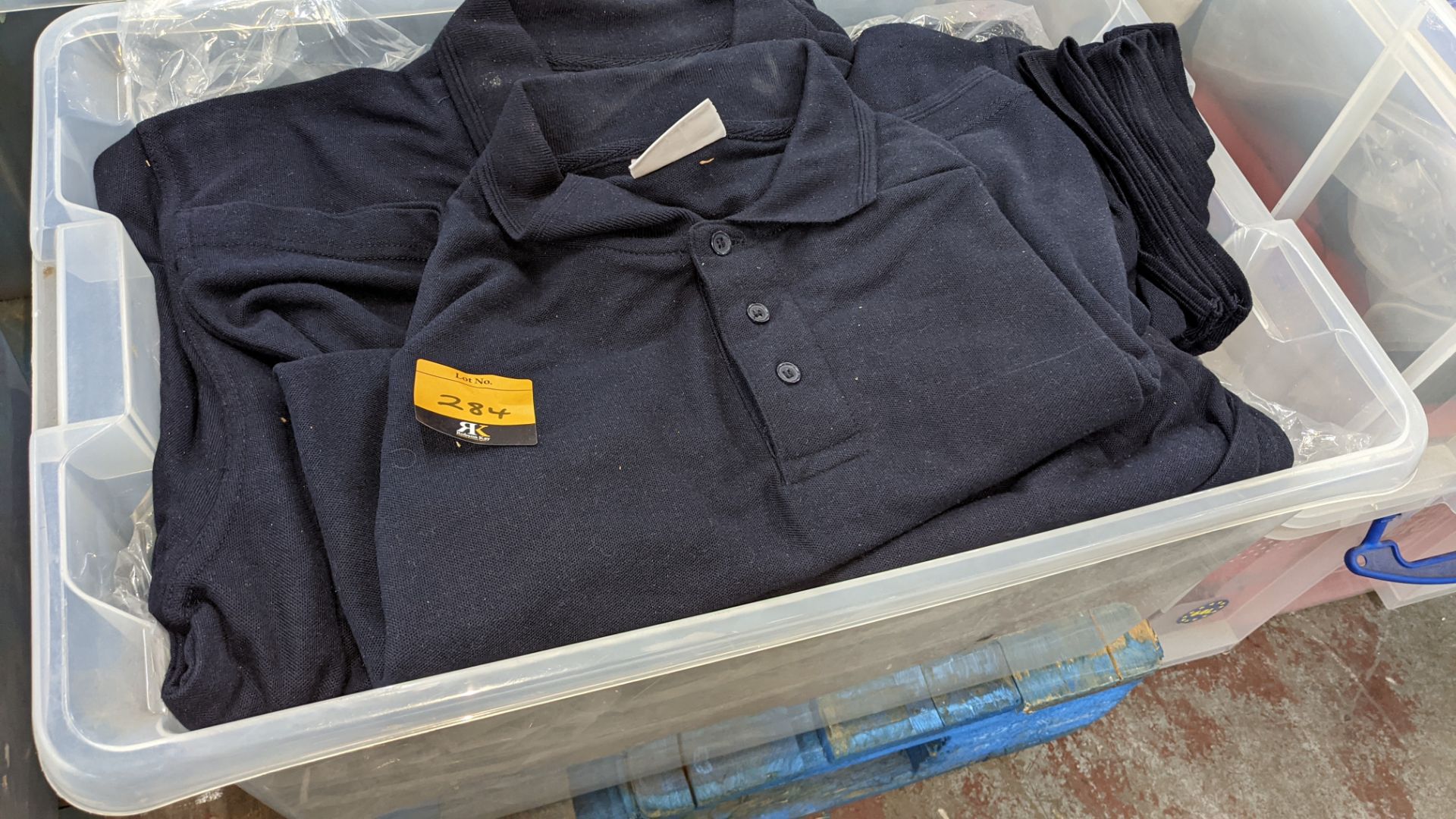 The contents of a crate of navy polo shirts. NB crate excluded