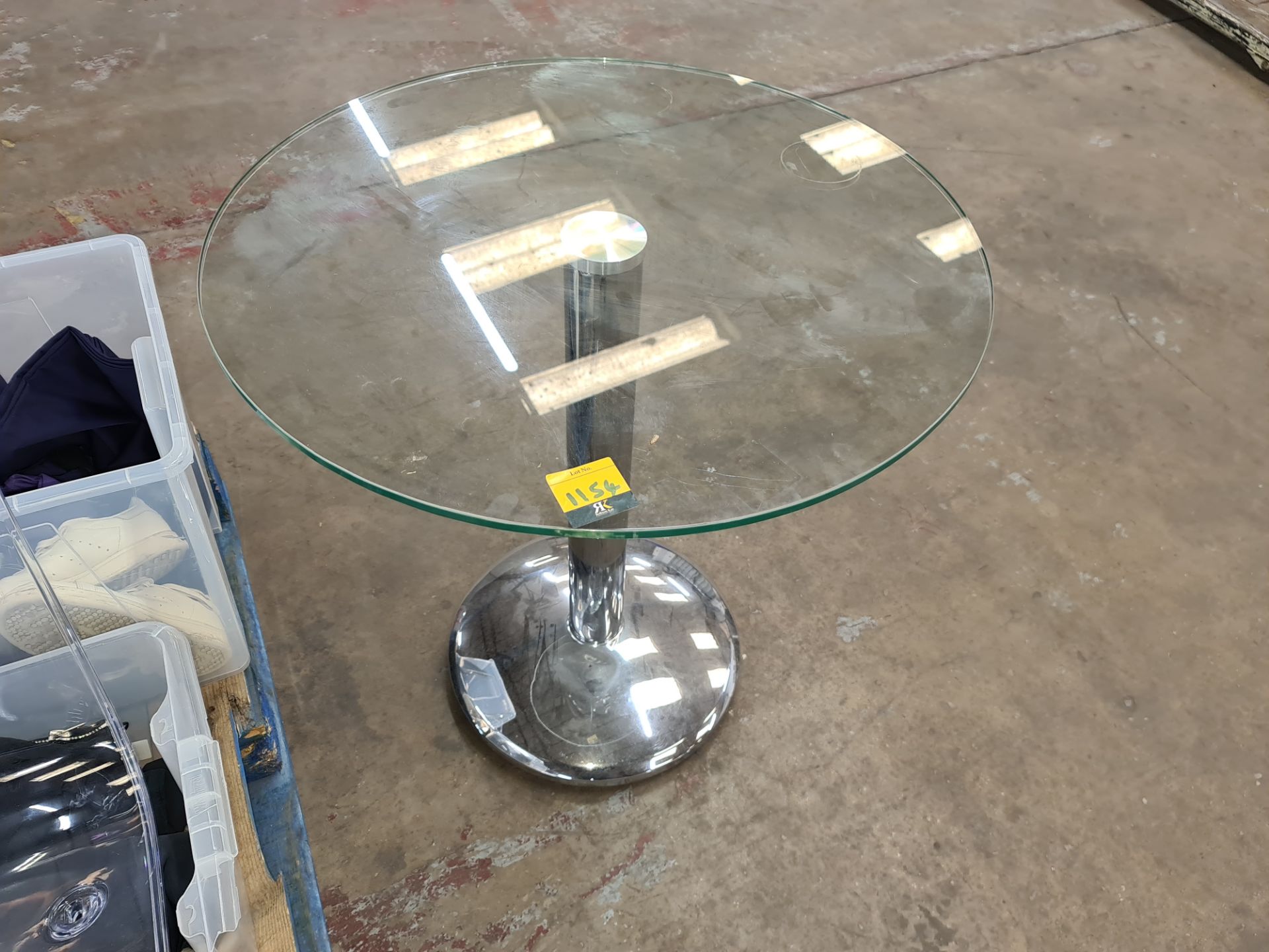 Circular glass table with single pedestal silver base