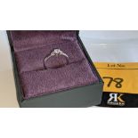 Platinum & diamond ring with a central stone flanked on the shoulders by smaller stones on either si