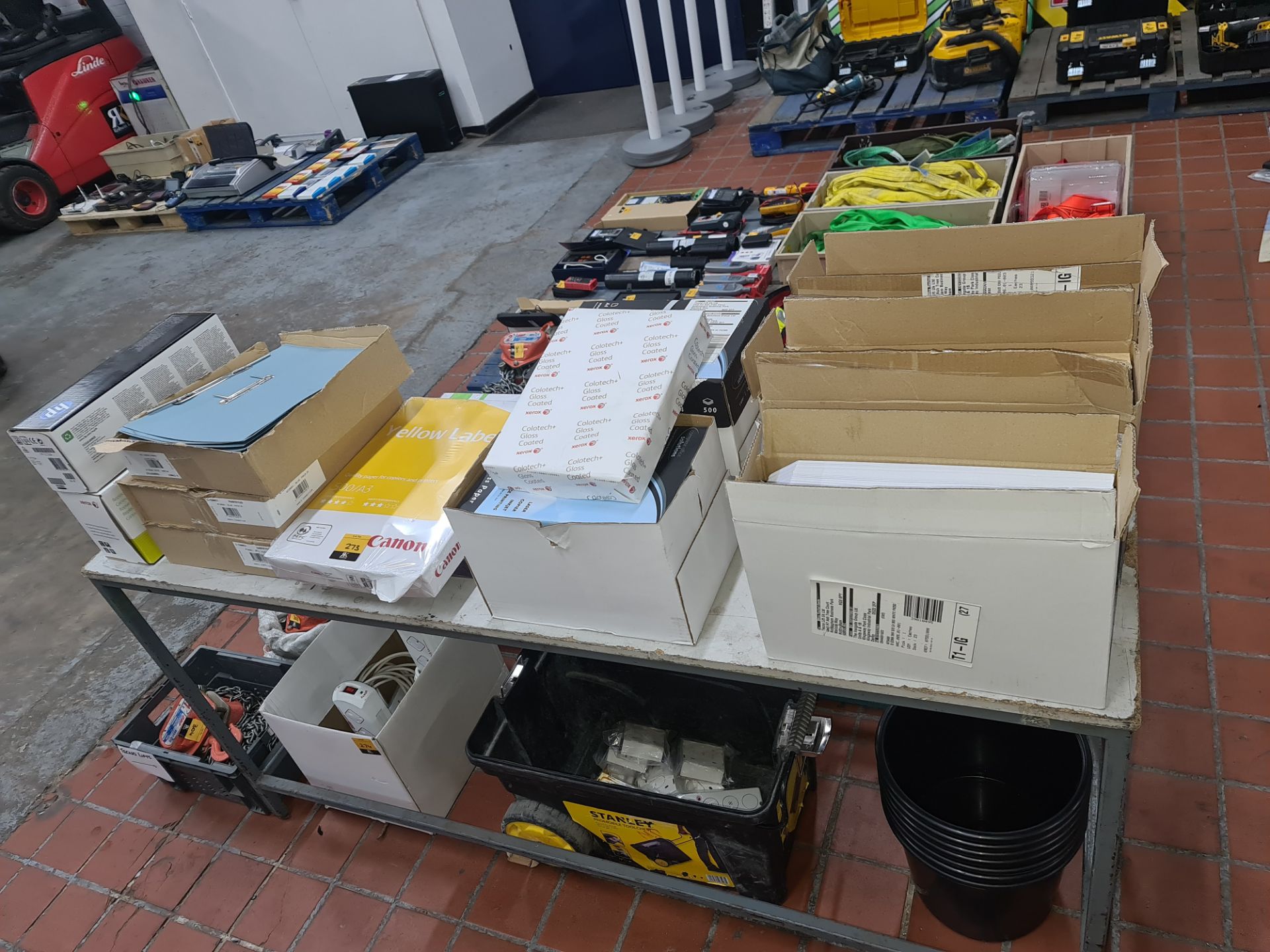 The contents of a table of assorted office supplies including printer cartridges, A4 & A3 paper, env