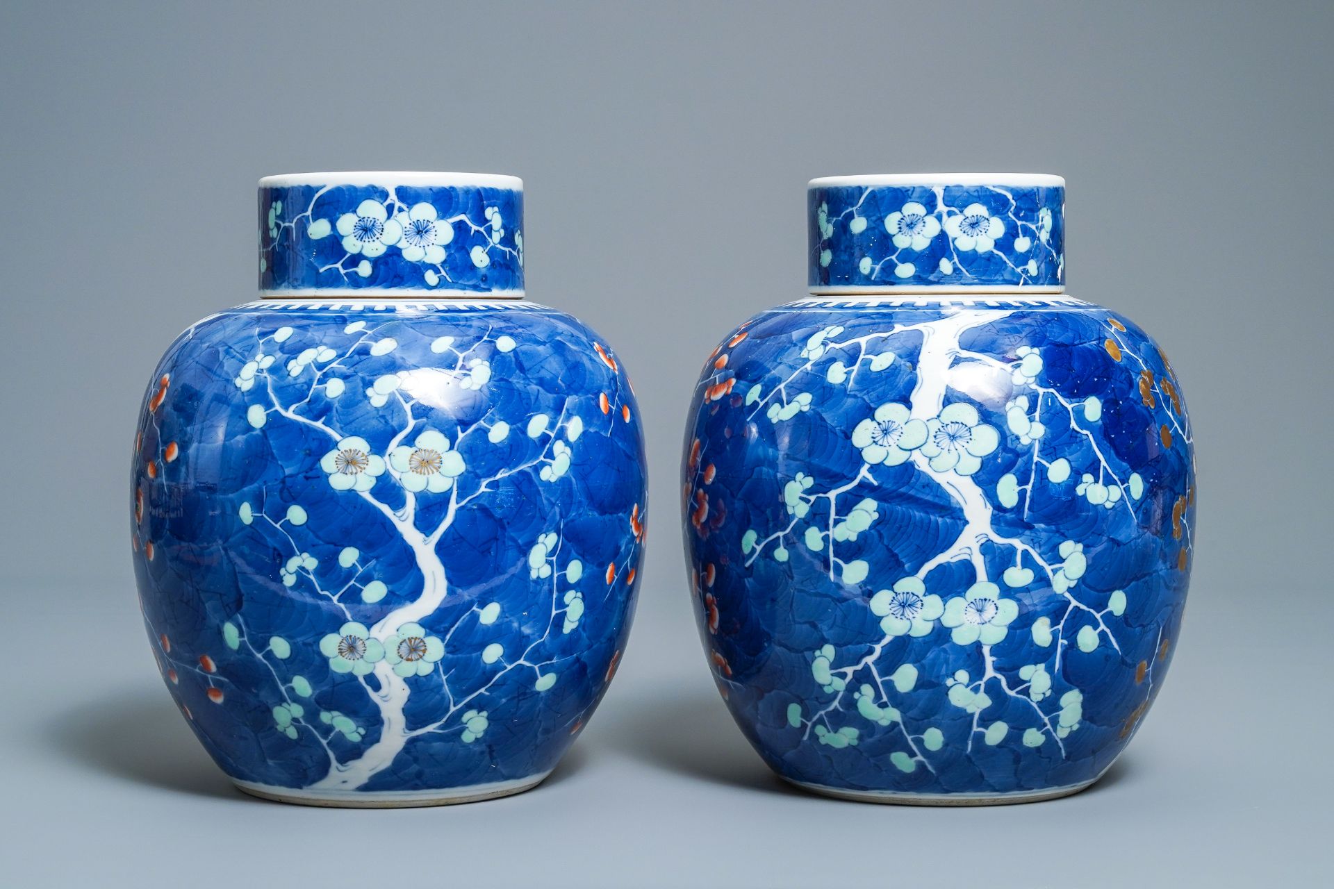 A pair of Chinese polychrome 'prunus on cracked ice' jars and covers, 19th C.