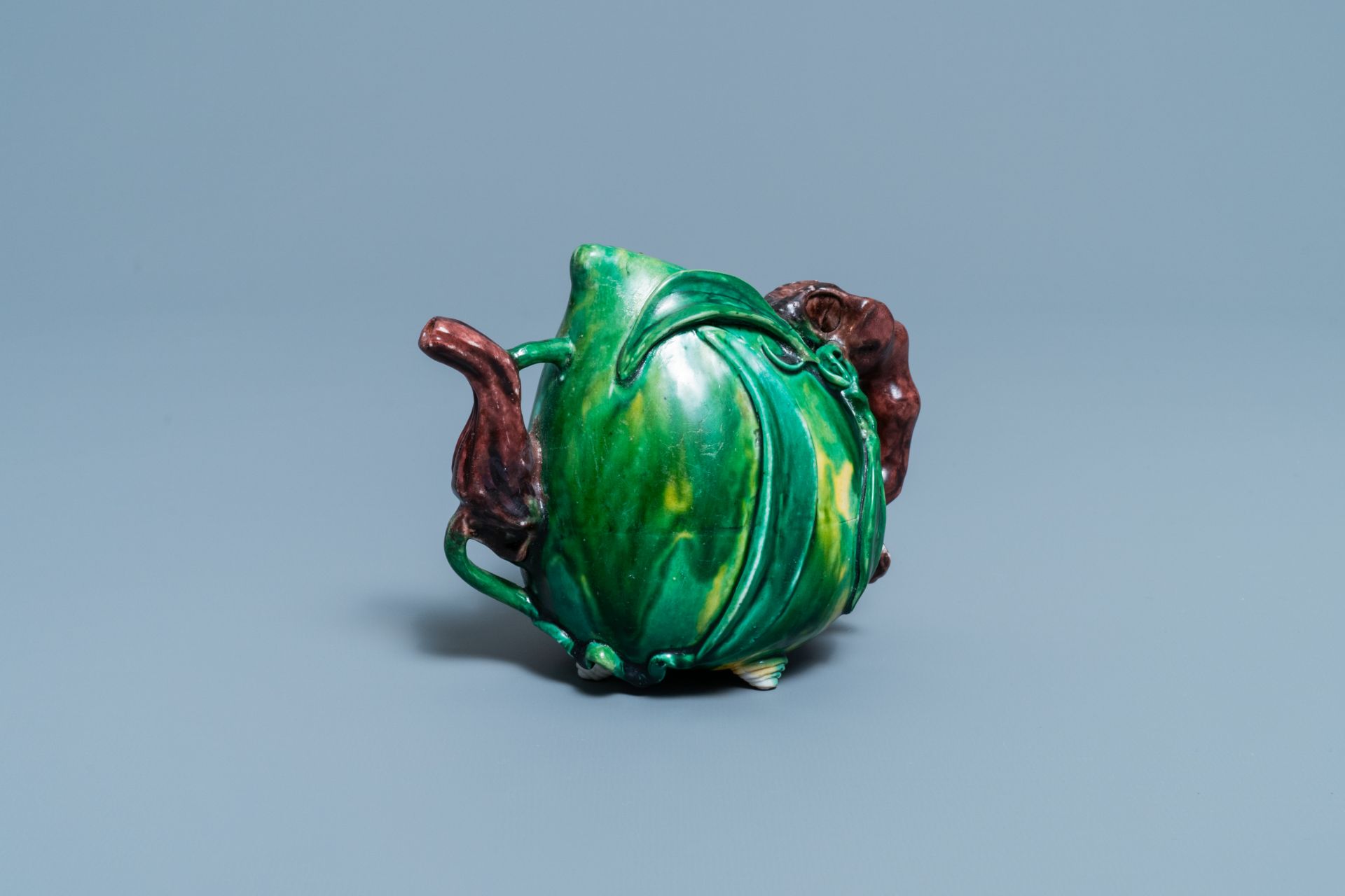 A Chinese verte biscuit peach-shaped 'cadogan' teapot, Kangxi