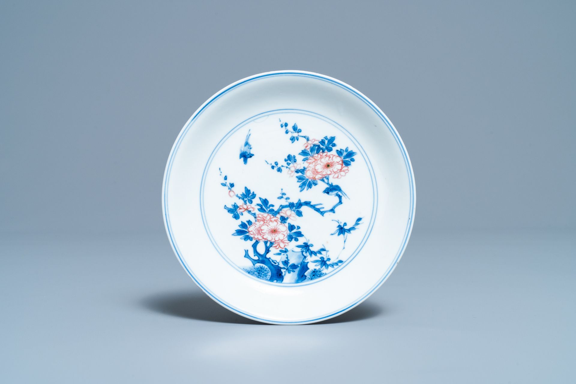 A Chinese blue, white and copper red saucer dish with floral design, Kangxi