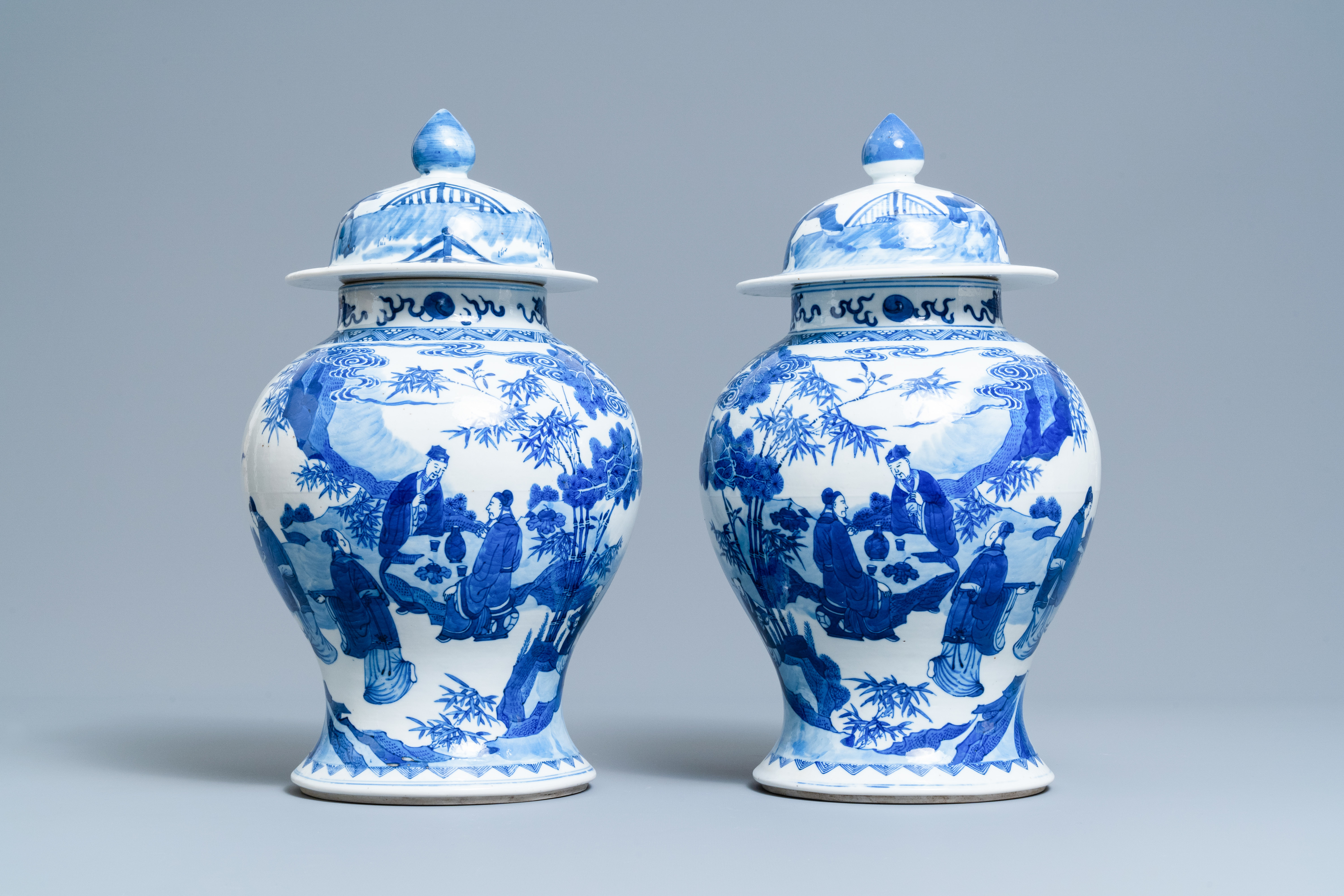 A pair of Chinese blue and white vases and covers with figures in a landscape, 19th C.