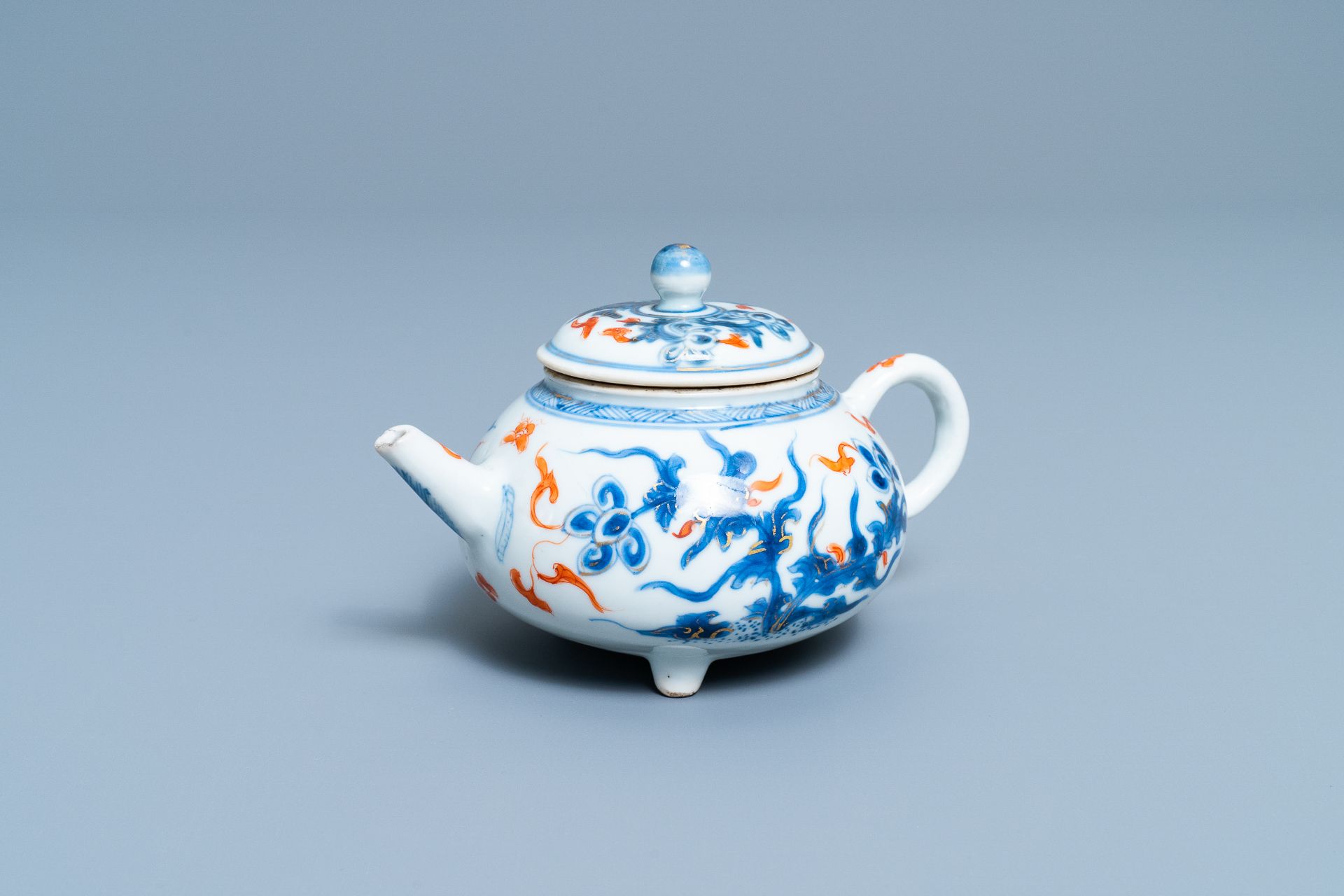 A Chinese blue, white, iron red and gilt tripod teapot and cover, Kangxi