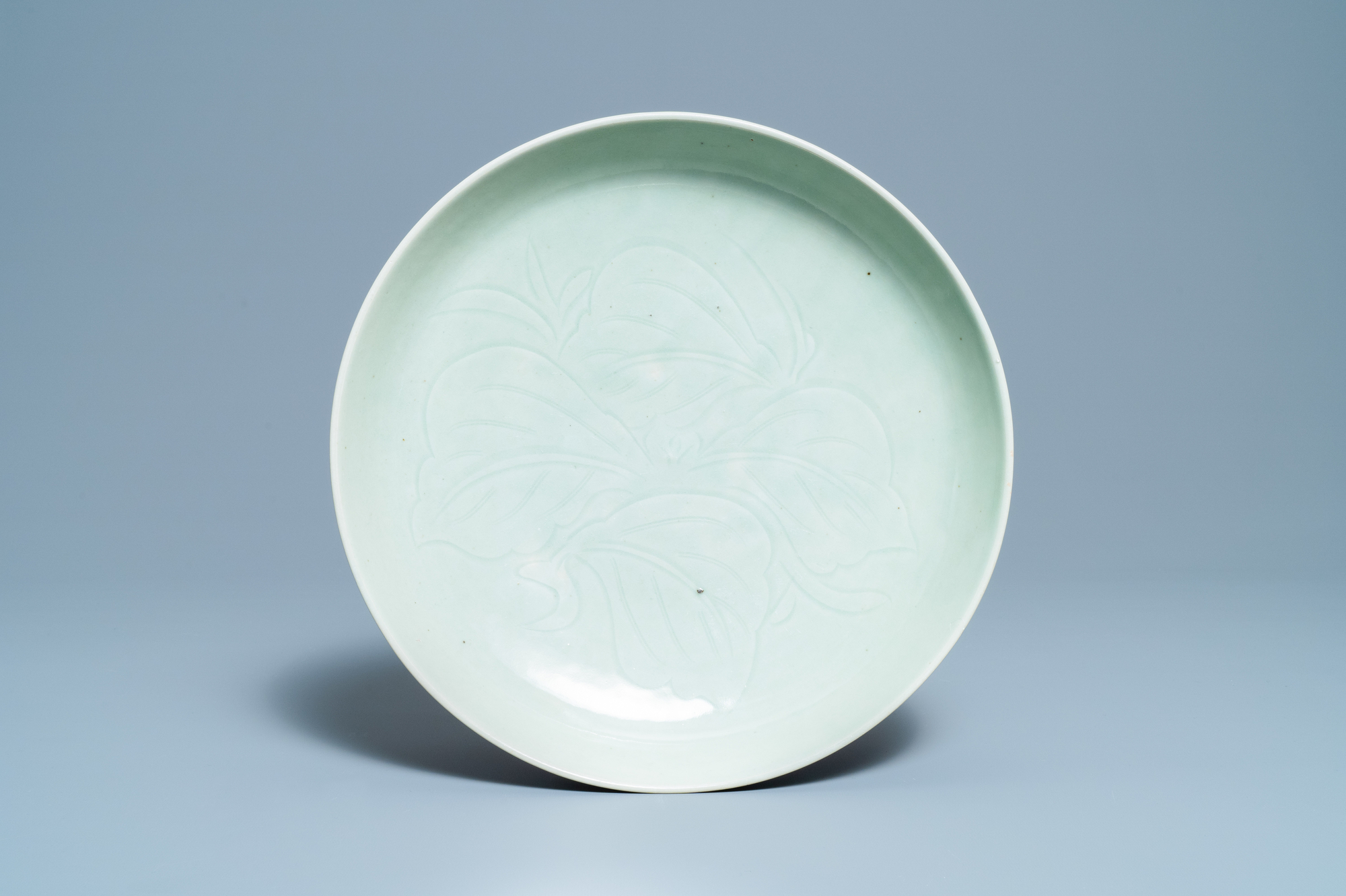 A Chinese monochrome celadon-glazed dish with underglaze floral design, 18/19th C.